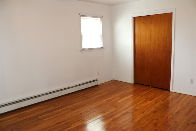 spare room featuring wood-type flooring, baseboards, and a baseboard radiator