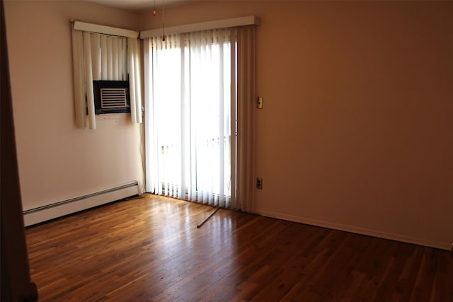 spare room featuring cooling unit, a baseboard heating unit, a healthy amount of sunlight, and wood finished floors