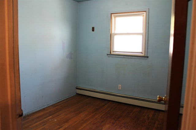 empty room featuring a baseboard heating unit and wood finished floors