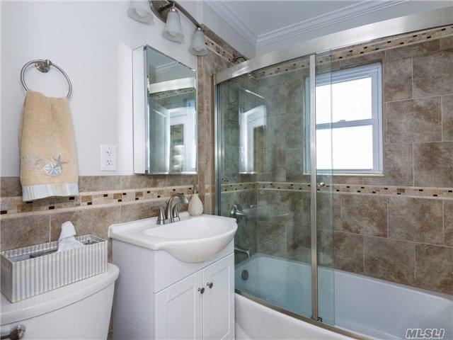 full bath featuring vanity, toilet, enclosed tub / shower combo, tile walls, and ornamental molding