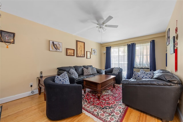 living area with baseboards, ceiling fan, and light wood-style flooring