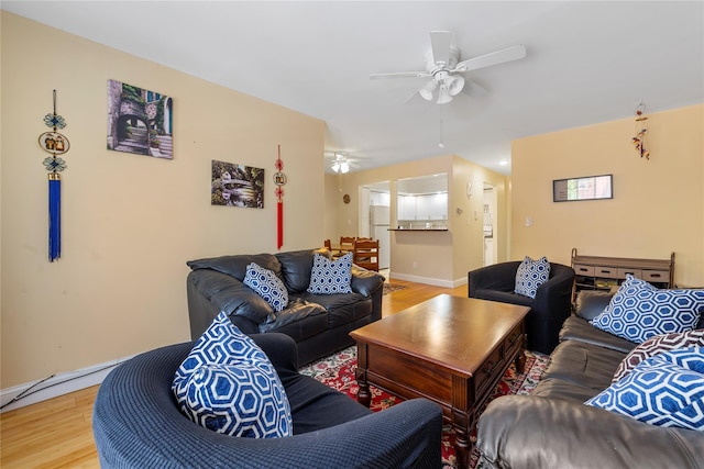living room featuring a ceiling fan, baseboards, and light wood-style flooring
