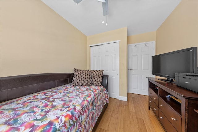 bedroom featuring light wood-type flooring, ceiling fan, lofted ceiling, and a closet