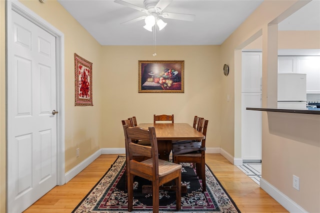 dining space featuring baseboards, a ceiling fan, and light wood-style flooring