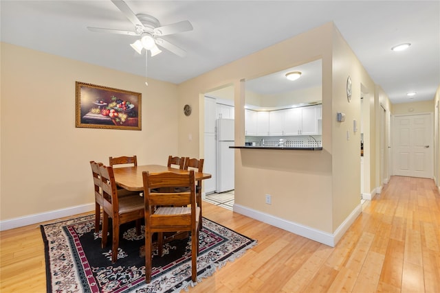dining area featuring baseboards, a ceiling fan, and light wood-style flooring