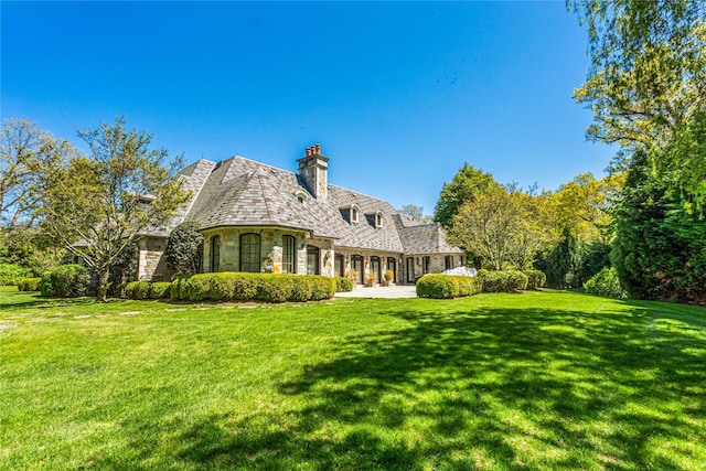 167 Brookville Rd, Brookville, NY 11545 - rear view of house featuring stone siding, a high end roof, a chimney, and a yard