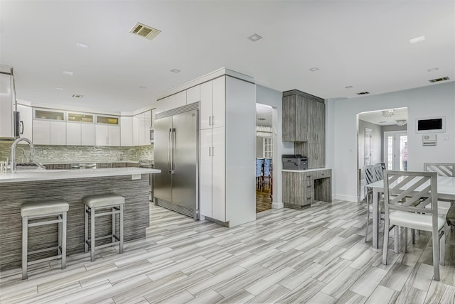 104 W Maple Ave, Monsey, NY 10952 - kitchen with a kitchen breakfast bar, built in fridge, a peninsula, decorative backsplash, and visible vents