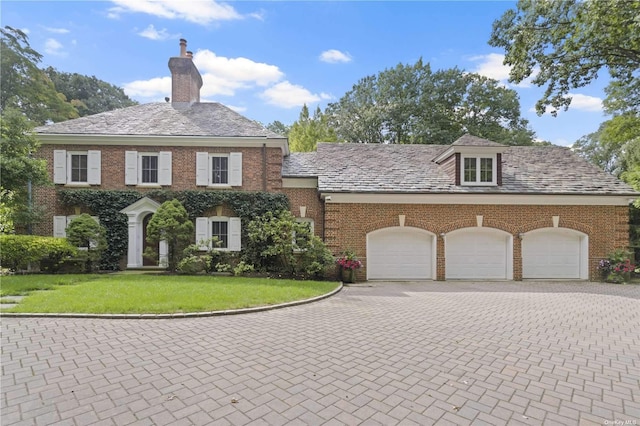 822 Bryant Ave, Roslyn Harbor, NY 11576 - colonial inspired home featuring a high end roof, a front yard, a chimney, brick siding, and an attached garage