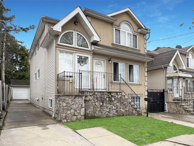 view of front of home with an outbuilding, stucco siding, driveway, and a front lawn