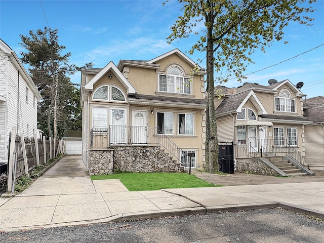 view of front of house featuring fence, an outdoor structure, and stucco siding