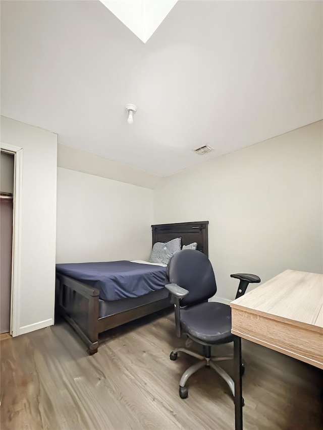 bedroom featuring baseboards, visible vents, and wood finished floors