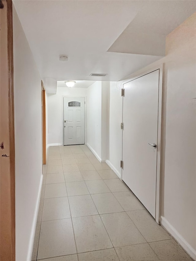 corridor featuring baseboards and light tile patterned flooring