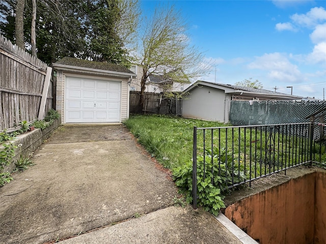 detached garage featuring fence and concrete driveway
