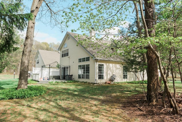3 Cloister Ln, Middle Island, NY 11953 - back of house featuring a lawn, a chimney, and roof with shingles