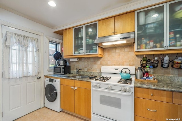 kitchen with washer / dryer, white gas range, stainless steel microwave, under cabinet range hood, and a sink