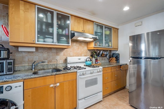 kitchen featuring ornamental molding, washer / clothes dryer, under cabinet range hood, a sink, and appliances with stainless steel finishes