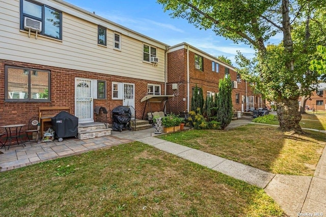 back of house featuring a lawn, a patio area, and brick siding