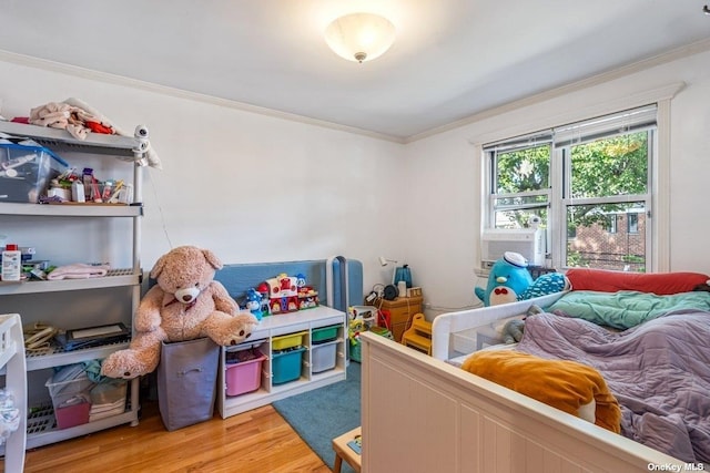 bedroom featuring ornamental molding, light wood finished floors, and cooling unit