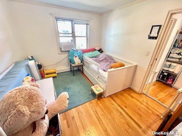 bedroom featuring baseboards, ornamental molding, and light wood-style floors