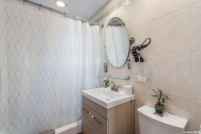 bathroom featuring toilet, tile walls, shower / bath combo with shower curtain, and vanity