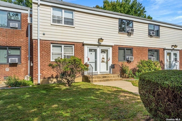 view of property featuring entry steps, cooling unit, a front lawn, and brick siding
