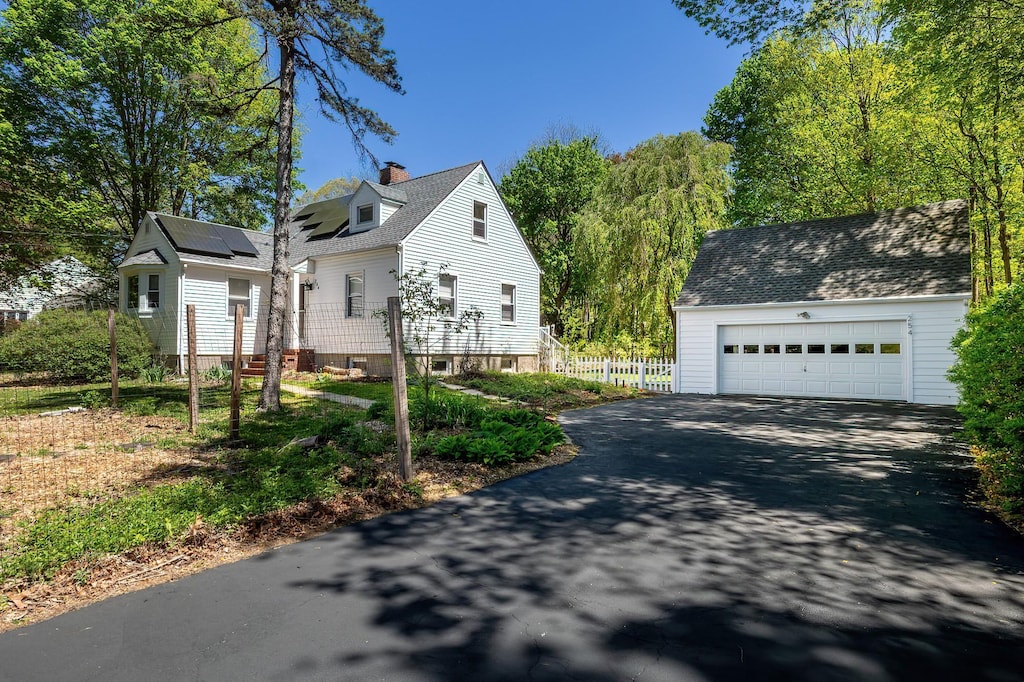 254 Lafayette Ave, Cortlandt Manor, NY 10567 - view of side of home featuring fence, a chimney, solar panels, an outbuilding, and a detached garage