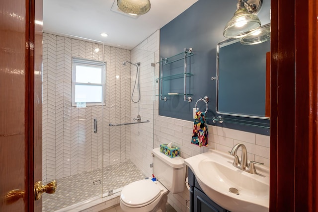 full bath with vanity, a shower stall, toilet, and tile walls
