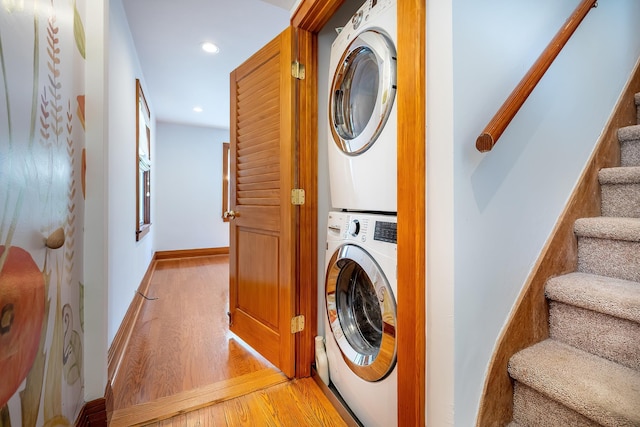 clothes washing area featuring laundry area, light wood finished floors, recessed lighting, baseboards, and stacked washer / dryer