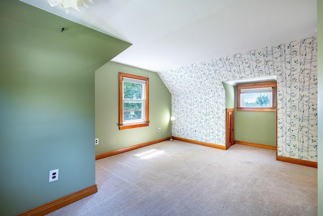 additional living space featuring baseboards, vaulted ceiling, wallpapered walls, and carpet