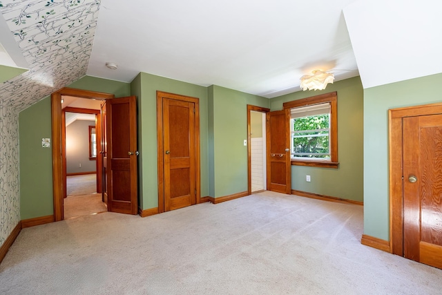 unfurnished bedroom featuring baseboards, carpet flooring, lofted ceiling, and a closet
