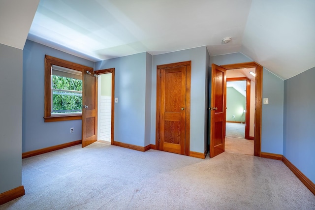 unfurnished bedroom with baseboards, carpet flooring, and lofted ceiling