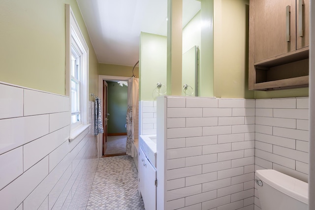 full bath with tile walls, tile patterned flooring, wainscoting, and toilet