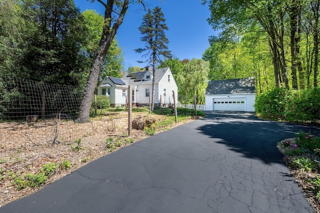 view of property exterior featuring a detached garage, fence, and an outbuilding