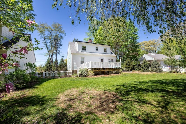 rear view of property with a lawn, fence, a wooden deck, and a chimney
