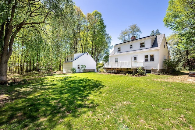 back of house featuring a lawn, a wooden deck, and a chimney