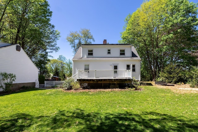 rear view of property featuring a lawn, fence, a chimney, and a deck