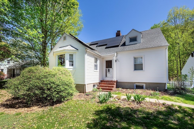bungalow featuring roof with shingles, solar panels, entry steps, and a chimney