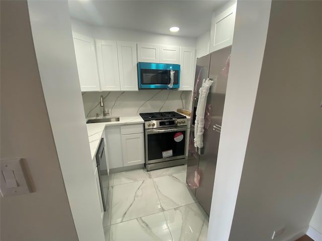 kitchen featuring a sink, marble finish floor, white cabinets, and stainless steel appliances