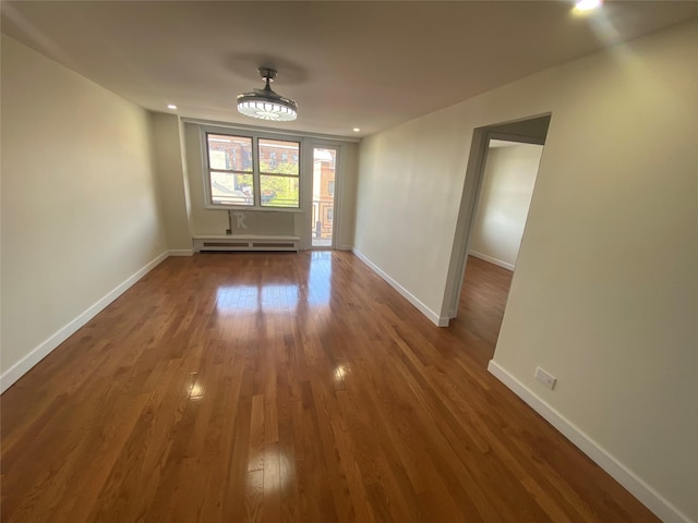 unfurnished dining area featuring baseboards, baseboard heating, and wood finished floors