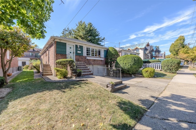 view of front of house with stairway, brick siding, fence, and a front lawn