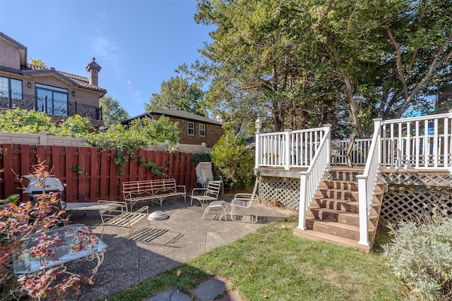 view of yard with fence, a wooden deck, a patio area, and stairway