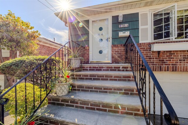 view of exterior entry featuring an attached garage and brick siding