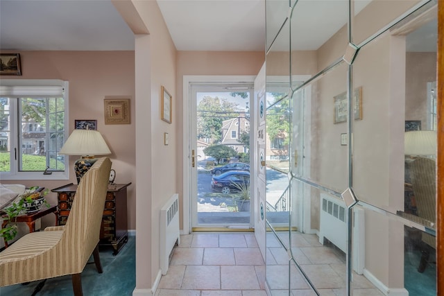 doorway featuring baseboards, radiator, and a wealth of natural light
