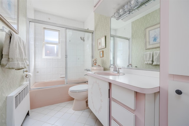 bathroom featuring tile patterned flooring, vanity, radiator, toilet, and enclosed tub / shower combo