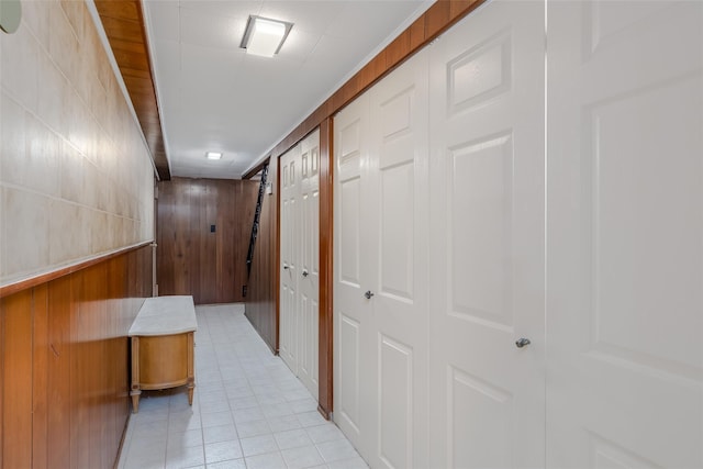 hall with wooden walls and light tile patterned floors