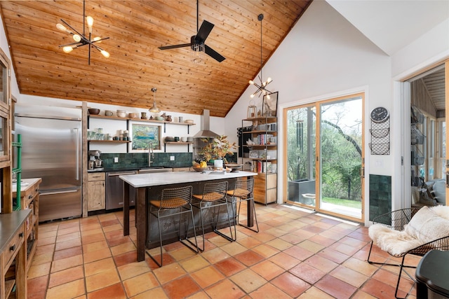 kitchen featuring wall chimney range hood, open shelves, appliances with stainless steel finishes, a kitchen breakfast bar, and high vaulted ceiling