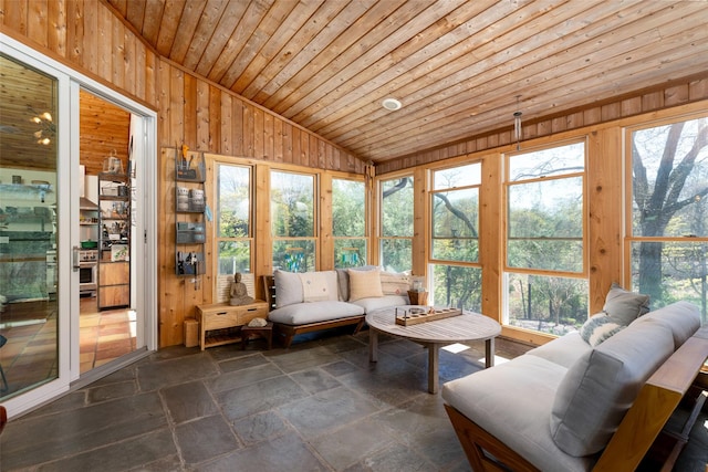 sunroom featuring a wealth of natural light, stone tile floors, and lofted ceiling