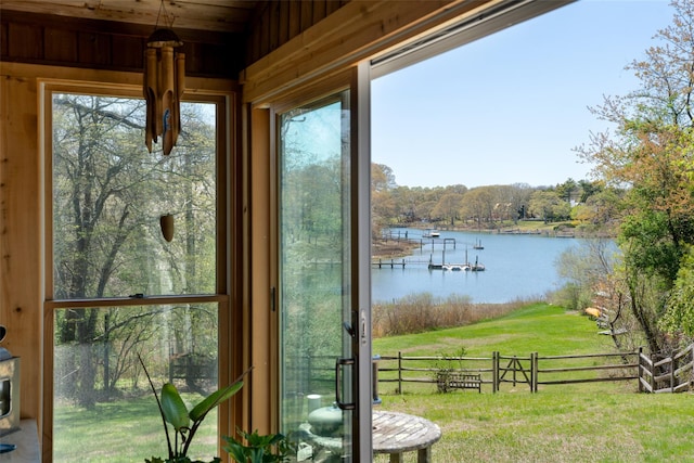 dock area with a yard, a water view, and fence