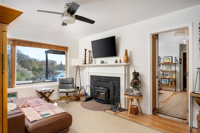 living area with baseboards, a ceiling fan, wood finished floors, and a wood stove