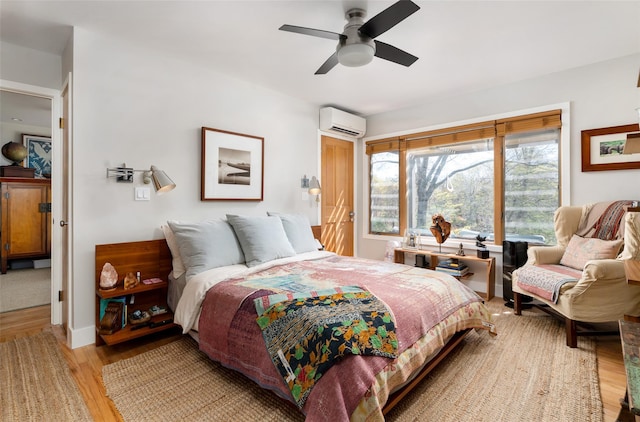 bedroom featuring a ceiling fan, light wood finished floors, and a wall unit AC